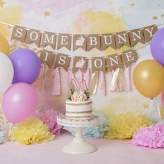 there is a cake on the table with balloons and bunnies around it that say some bunny is one