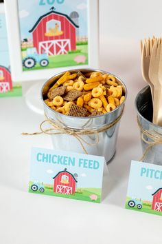 two buckets filled with cereal sitting on top of a table next to cards and utensils