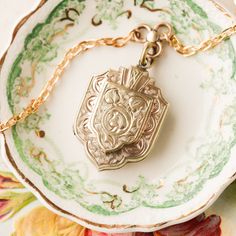 This one-of-a-kind necklace is composed of: Victorian, gold filled locket and watch fob connecting link from the late 1800s. The locket features hand engraved details on the front and back of the piece. This piece was originally made and sourced in England. This necklace measures a standard 18” on a modern 14k gold filled chain. The pendant measures 1.25" in length. Heirloom Style Jewelry With Vintage Charm, Antique Yellow Gold Necklace With Historical Design, Victorian Oval Locket Necklace With Vintage Charm, Oval Victorian Locket Necklace With Vintage Charm, Heirloom Brass Jewelry With Vintage Charm, Heirloom Style Locket Pendant Jewelry, Antique Medallion Jewelry With Historical Design, Heirloom Locket Pendant Jewelry, Classic Locket Necklace For Vintage Collection