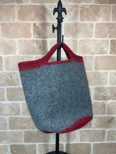 a gray and red bag hanging from a hook on a brick wall with a coat rack