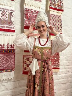 a woman wearing an old fashioned dress and holding her hands up in the air while smiling