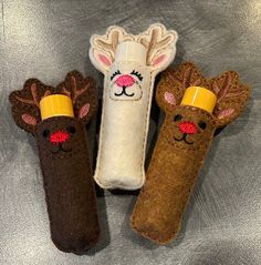 three stuffed animals are sitting next to each other on a silver surface, one is brown and the other is white