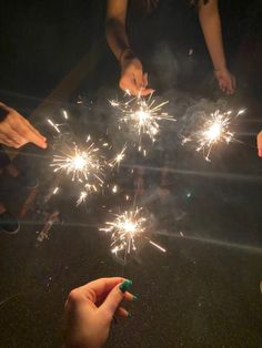 several people holding sparklers in their hands and pointing them at the firecrackers