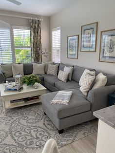 a living room with gray couches and white coffee table in front of two windows