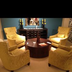 a living room with yellow chairs and a coffee table in front of a blue wall