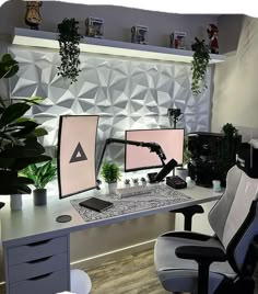 two computer monitors sitting on top of a desk next to a chair and potted plant