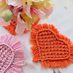 two crocheted hearts are sitting next to each other on a white wooden surface