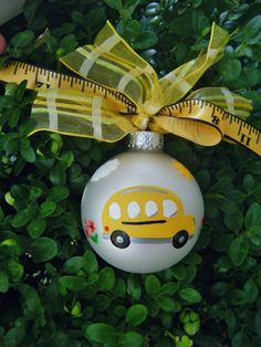 a christmas ornament with a yellow bus painted on it and a measuring tape