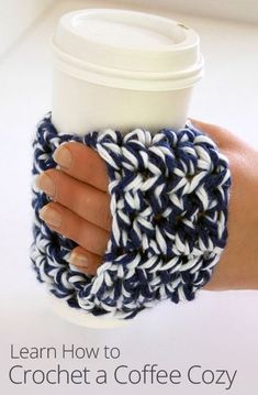 a woman's hand holding a coffee cup cozy in blue and white crochet