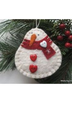 a snowman ornament hanging from a christmas tree with red hearts on it