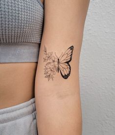 a woman's arm with a butterfly and flower tattoo on the left side of her arm