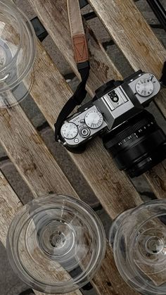 a camera and some wine glasses on a wooden table