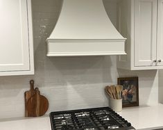 a stove top oven sitting inside of a kitchen next to wooden cutting boards and utensils