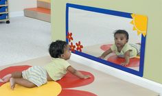 two toddlers playing in front of a mirror with their feet on the ground and looking at each other