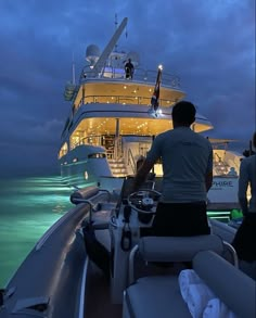 two people standing on the back of a boat at night