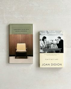 two books sitting next to each other on top of a white wall with a chair in front of it