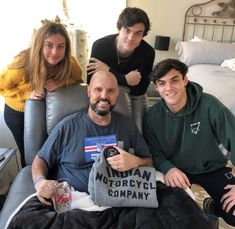 three people sitting on a couch posing for the camera