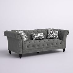 a gray couch with black and white pillows on it's back legs, sitting in front of a grey wall