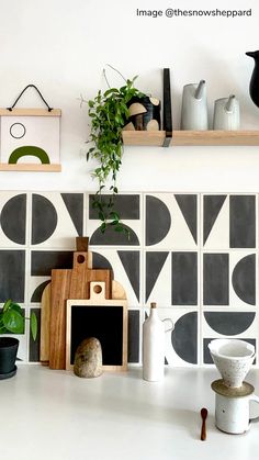 the kitchen counter is decorated with black and white tiles, potted plants and other items