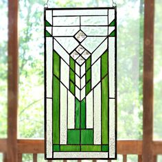 a stained glass window hanging on the side of a wooden porch with trees in the background