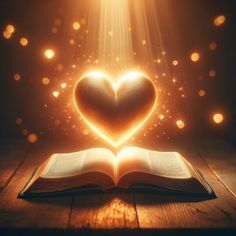 an open book with a heart shaped light coming out of it on a wooden table