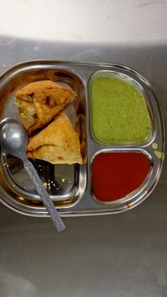 a metal tray filled with different types of food next to sauces and spoons