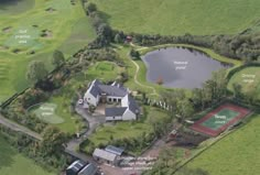 an aerial view of a house and tennis court with lots of green space around it