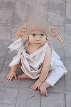 a baby dressed up like an angel sitting on the ground