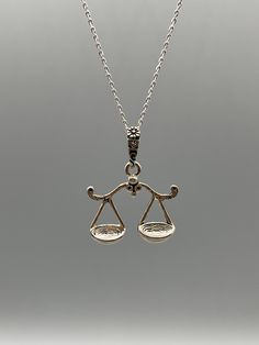 a silver necklace with an image of a balance scale on the front and back sides