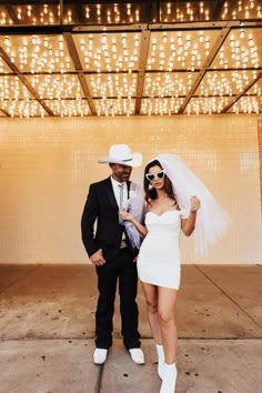 a man and woman dressed up in cowboy hats, dress clothes, and white shoes