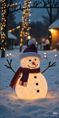 a snowman with a hat and scarf on in the snow next to some christmas lights