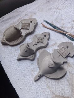 three clay elephants sitting on top of a table next to some scissors and yarn needles