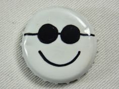 a white button with black eyes and a smiley face drawn on the front, sitting on a white surface