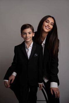 a woman standing next to a boy in a suit