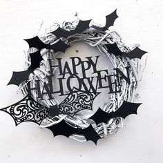 a happy halloween wreath hanging on the side of a white wall with bats around it