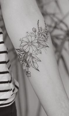 a black and white photo of a woman's arm with flowers tattooed on it