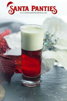 a shot glass filled with liquid sitting on top of a table next to white flowers