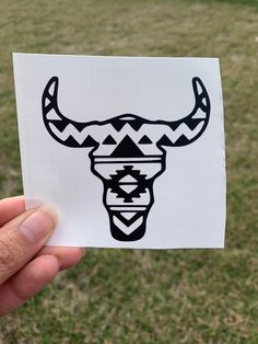 a hand holding up a sticker with an image of a bull's head