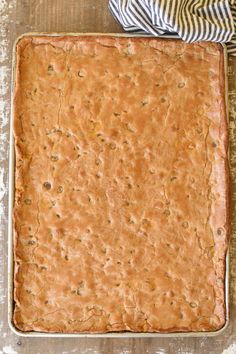 an uncooked square cake sitting on top of a wooden table next to a striped napkin