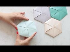 two hands are holding origami pieces on a table