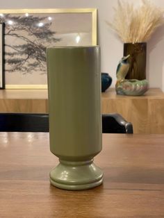 a green vase sitting on top of a wooden table