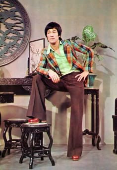 a man sitting on top of a stool next to a plant