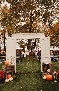 an outdoor ceremony with pumpkins and other decorations on the grass in front of trees