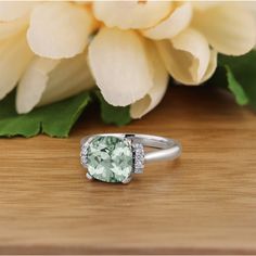 a green ring sitting on top of a wooden table next to a bouquet of flowers