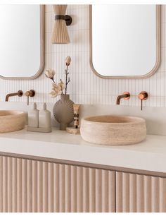 two bathroom sinks with mirrors above them and vases on the counter in front of them