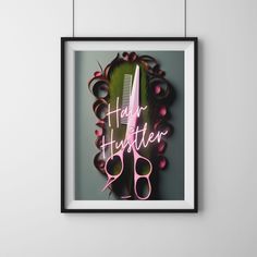 a black frame with pink scissors and hair clippings hanging on it's wall