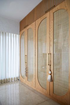 an empty room with large wooden doors and white drapes on the window sill