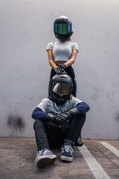 a woman sitting on the ground next to a man wearing a helmet