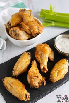 chicken wings with dip and celery on a black slate platter next to it