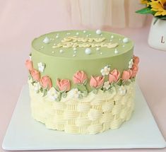 a green cake with flowers on it sitting on a table